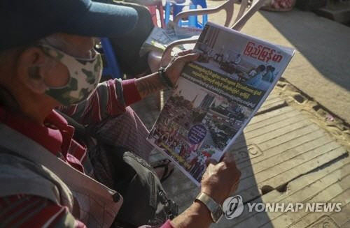 미얀마 옛 수도 양곤의 한 시민이 2일 "1년간 국가비상사태와 대통령 권한대행 군부에 권력 이양"이라는 제목의 신문 1면 기사를 살펴보고 있다. 양곤 AP=연합뉴스